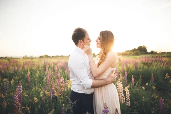 Panna młoda i pan młody, rissing o zachodzie słońca na polu piękne kwiaty, romantyczny ślub para — Zdjęcie stockowe