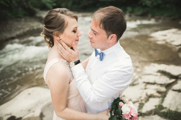 Элегантный стильный счастливая брюнетка невеста и великолепный жених на фоне красивого водопада в горах — стоковое фото