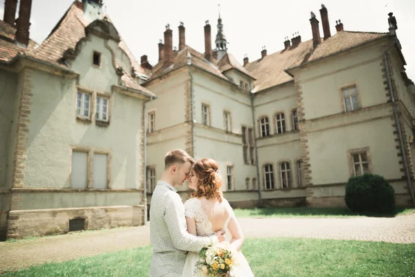 Novomanželům pózy a líbání s staré pevnosti na pozadí — Stock fotografie
