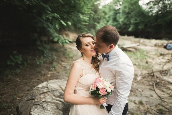 Elegante noivo elegante doce e noiva perto do rio com pedras. Casamento casal apaixonado — Fotografia de Stock