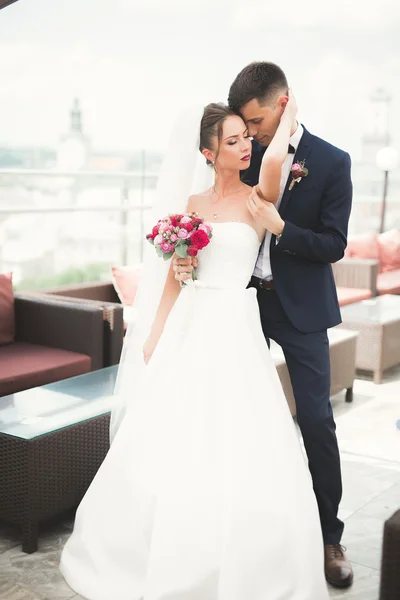 Ravissant couple de mariage heureux, mariée avec longue robe blanche posant dans la belle ville — Photo