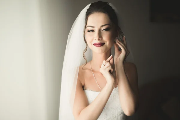 Hermosa novia joven con maquillaje y peinado en el dormitorio, mujer recién casada preparación final para la boda. Chica feliz esperando novio. Retrato de enfoque suave —  Fotos de Stock