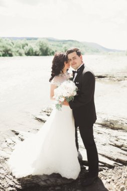 Zarif nazik şık damat ve gelin taşlarla Nehri yakınında. Evlilik çift aşık
