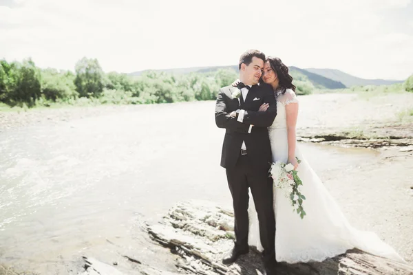 신부 및 신랑 아름 다운 웨딩 부케를 들고 강 근처 포즈 — 스톡 사진