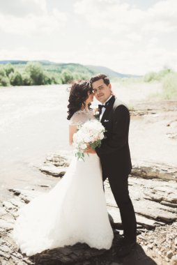 Gelin ve damat güzel düğün buket tutarak. Nehir kenarında poz