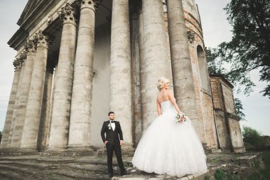 Güzel, romantik bir düğün. Yeni evliler. Eski kalenin yakınlarında sarılıyorlar.