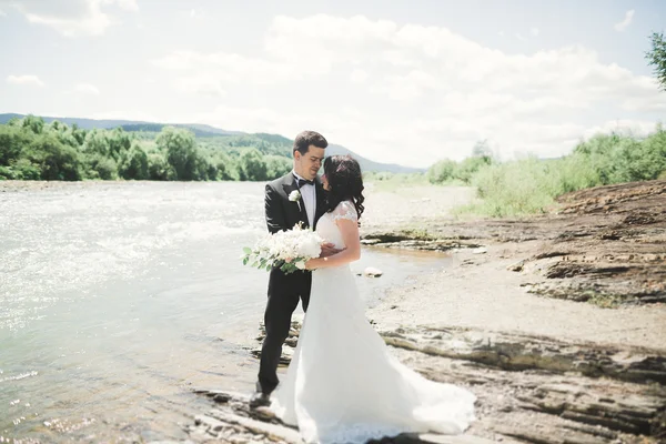 Elegante sanfte stilvolle Bräutigam und Braut in Flussnähe mit Steinen. Hochzeitspaar verliebt — Stockfoto