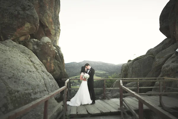 Verliebtes Hochzeitspaar küsst und umarmt sich in der Nähe von Felsen in schöner Landschaft — Stockfoto