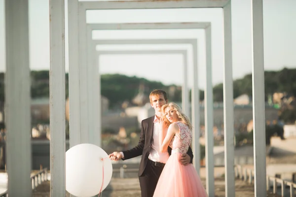 Retrato ao ar livre muito ensolarado de jovem casal elegante enquanto se beija no telhado com vista para a cidade — Fotografia de Stock