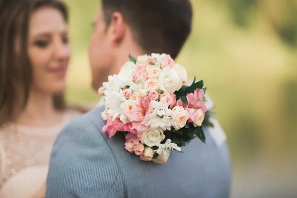 新娘和新郎抱着美丽的婚礼花束。湖森林 — 图库照片