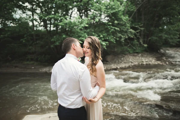 Élégant marié élégant doux et la mariée près de la rivière avec des pierres. Couple de mariage amoureux — Photo