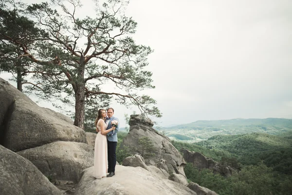 Boda pareja enamorada besándose y abrazándose cerca de rocas en hermoso paisaje — Foto de Stock