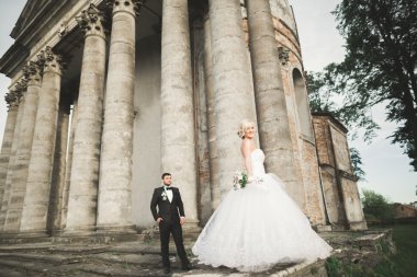 Güzel, romantik bir düğün. Yeni evliler. Eski kalenin yakınlarında sarılıyorlar.