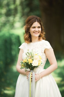 Gelin. Güzel sarışın kadın çiçek çelenk ve buket sıcak yaz gününde park