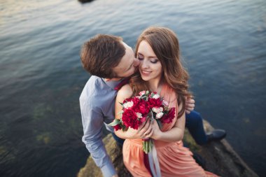 Mavi Denizi çevresinde büyük bir taş üzerinde oturan Düğün çifti