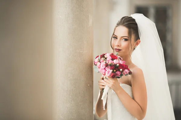 Beautiful bride with wedding bouquet posing in old city — Stock Photo, Image