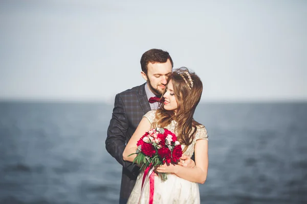 Pareja de recién casados caminando en la playa al atardecer . — Foto de Stock