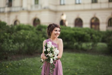 Güzel gelin, kız açık havada buket ile poz