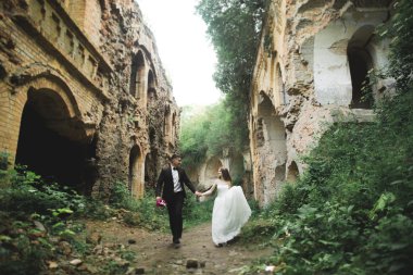 Güzel, romantik bir düğün. Yeni evliler. Eski kalenin yakınlarında sarılıyorlar.