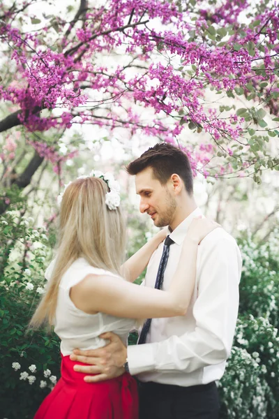 Stijlvolle mooie verheugd huwelijksfeest paar kussen en omhelzen in botanische tuin — Stockfoto