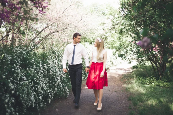 Unga vackra par kyssas och kramas nära träd med blossom i sommaren park — Stockfoto