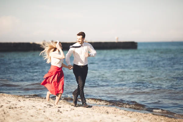 Joven pareja feliz caminando por la playa sonriendo abrazándose unos a otros. Historia de amor — Foto de Stock