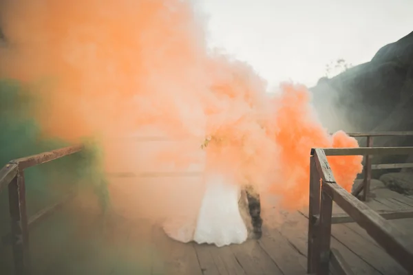 結婚式のカップルは、その背後にある色を吸うと岩の近くポーズ — ストック写真