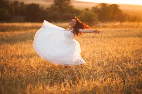 Joyeux beau jeune mariée dehors sur une prairie d'été au coucher du soleil — Photo