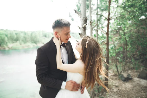 Boda pareja enamorada besándose y abrazándose cerca de rocas en hermoso paisaje —  Fotos de Stock