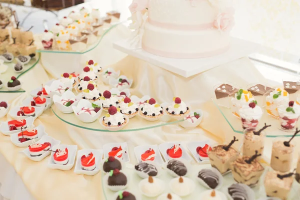 Delicious and tasty dessert table with cupcakes shots at reception closeup — Stock Photo, Image