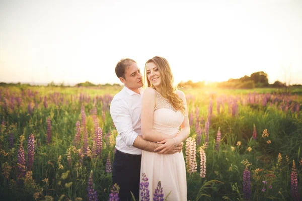 Emocional hermosa novia abrazando novio recién casado desde detrás de la puesta del sol en un primer plano de campo —  Fotos de Stock