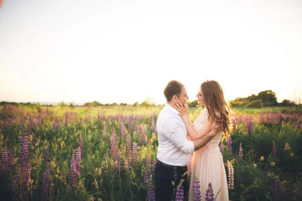 Para młoda ślub, chodzenie na pole z kwiatami — Zdjęcie stockowe