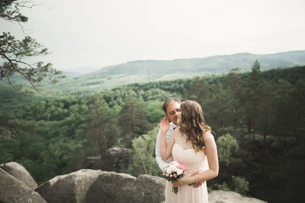 Splendida sposa, sposo baciare e abbracciare vicino alle scogliere con vista mozzafiato — Foto Stock