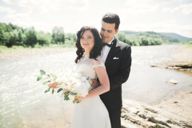 Gelin ve damat güzel düğün buket tutarak. Nehir kenarında poz