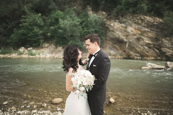 Zarif nazik şık damat ve gelin taşlarla Nehri yakınında. Evlilik çift aşık