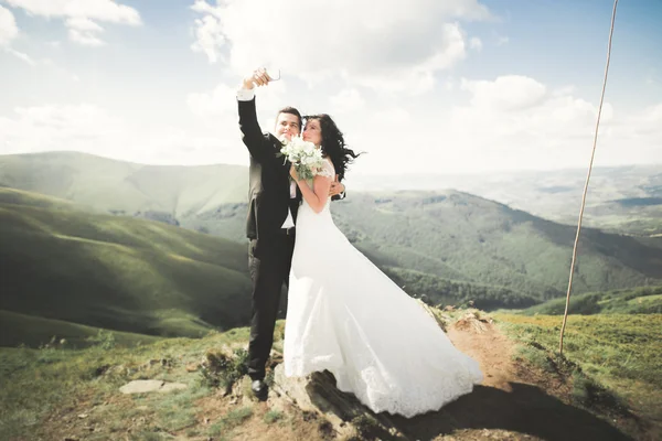 Красивая молодая свадебная пара делает селфи на фоне гор — стоковое фото