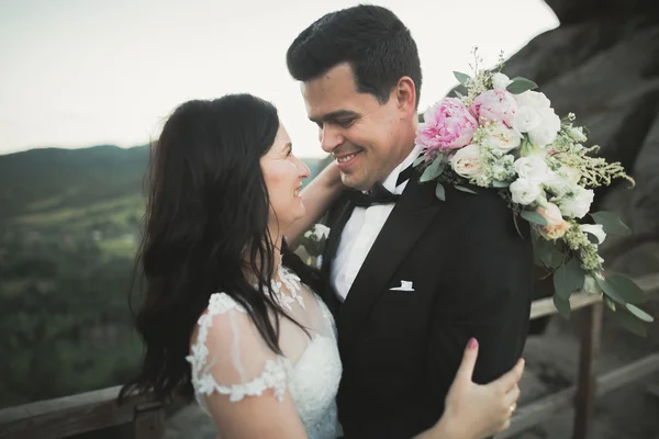 Splendida sposa, sposo baciare e abbracciare vicino alle scogliere con vista mozzafiato — Foto Stock