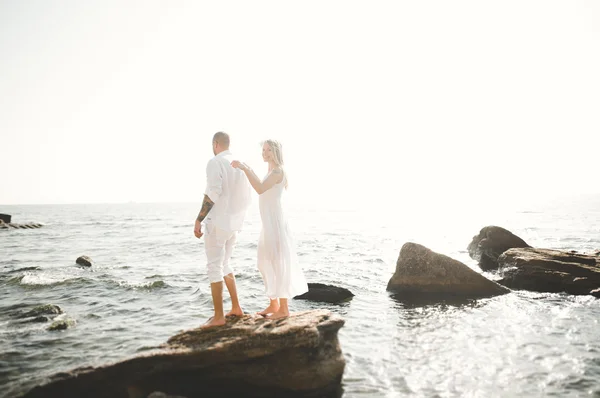 刚结婚的婚礼夫妇海滩上散步，在日落时分. — 图库照片