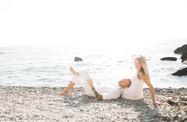 Boda pareja besándose y abrazándose en rocas cerca de mar azul — Foto de Stock