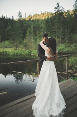 Sevimli gelin, dağlar ve günbatımı manzara Gölü üzerinde zarif damat. Muhteşem Düğün çifti