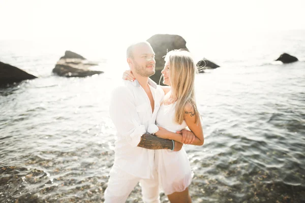 Matrimonio coppia baci e abbracci su rocce vicino al mare blu — Foto Stock