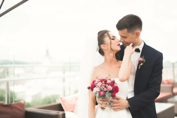 Hermosa pareja, novia y novio posando en el balcón con el fondo de la ciudad vieja — Foto de Stock