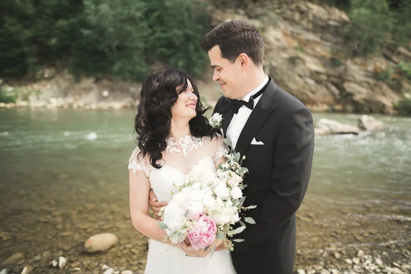 Наречений і наречений тримають гарний весільний букет. Позування біля річки — стокове фото