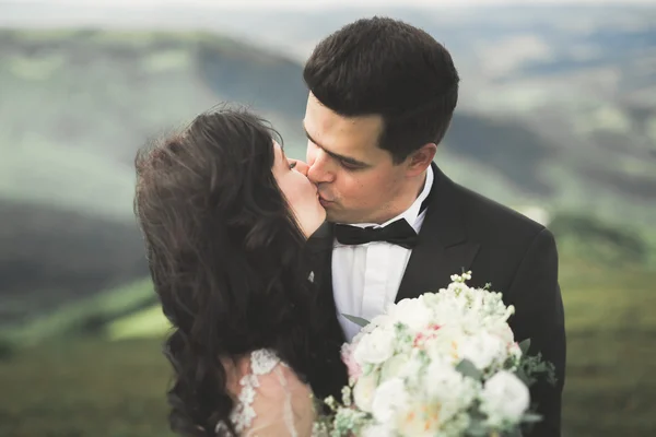 Όμορφος γάμος ζευγάρι φιλιά και αγκάλιασμα κοντά στο βουνό με τέλεια θέα — Φωτογραφία Αρχείου