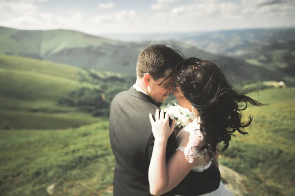 Yeni evli çift, gelin ve damat öpüşüyor, mükemmel dağ manzarasında sarılıyorlar, mavi gökyüzü — Stok fotoğraf