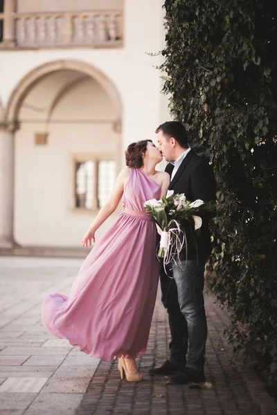 Happy wedding couple, groom, bride with pink dress hugging and smiling each other on the background walls in castle — Stock Photo, Image