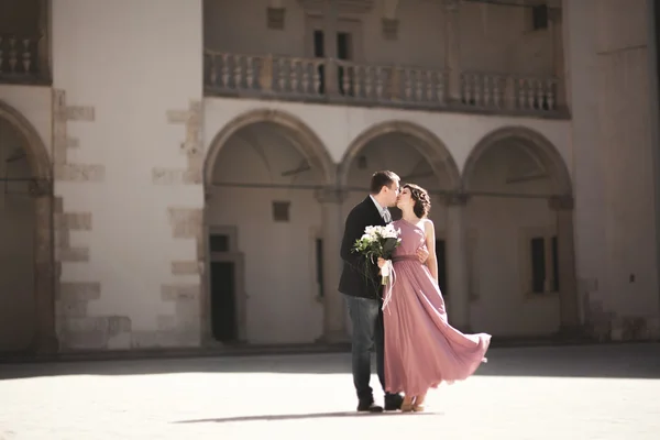 Felice coppia di nozze, sposo, sposa con abito rosa che si abbracciano e si sorridono sulle pareti di sfondo del castello — Foto Stock