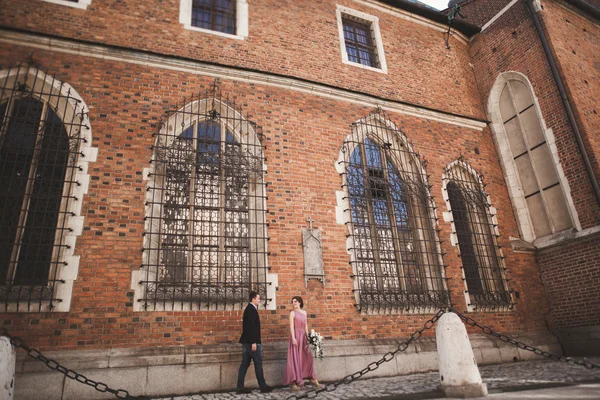 Superbe couple de mariage, marié et mariée avec robe rose marchant dans la vieille ville de Cracovie — Photo