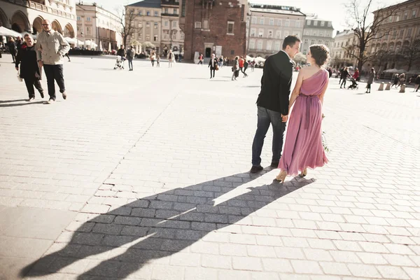 Wedding. beautiful couple, bride with pink dress walking in the old city Krakow, their shadows — Stock Photo, Image