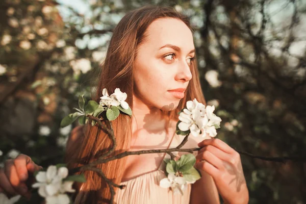 Junges schönes Mädchen in einem langen Kleid und einem Blumenkranz in der Nähe des Fliederstrauches — Stockfoto